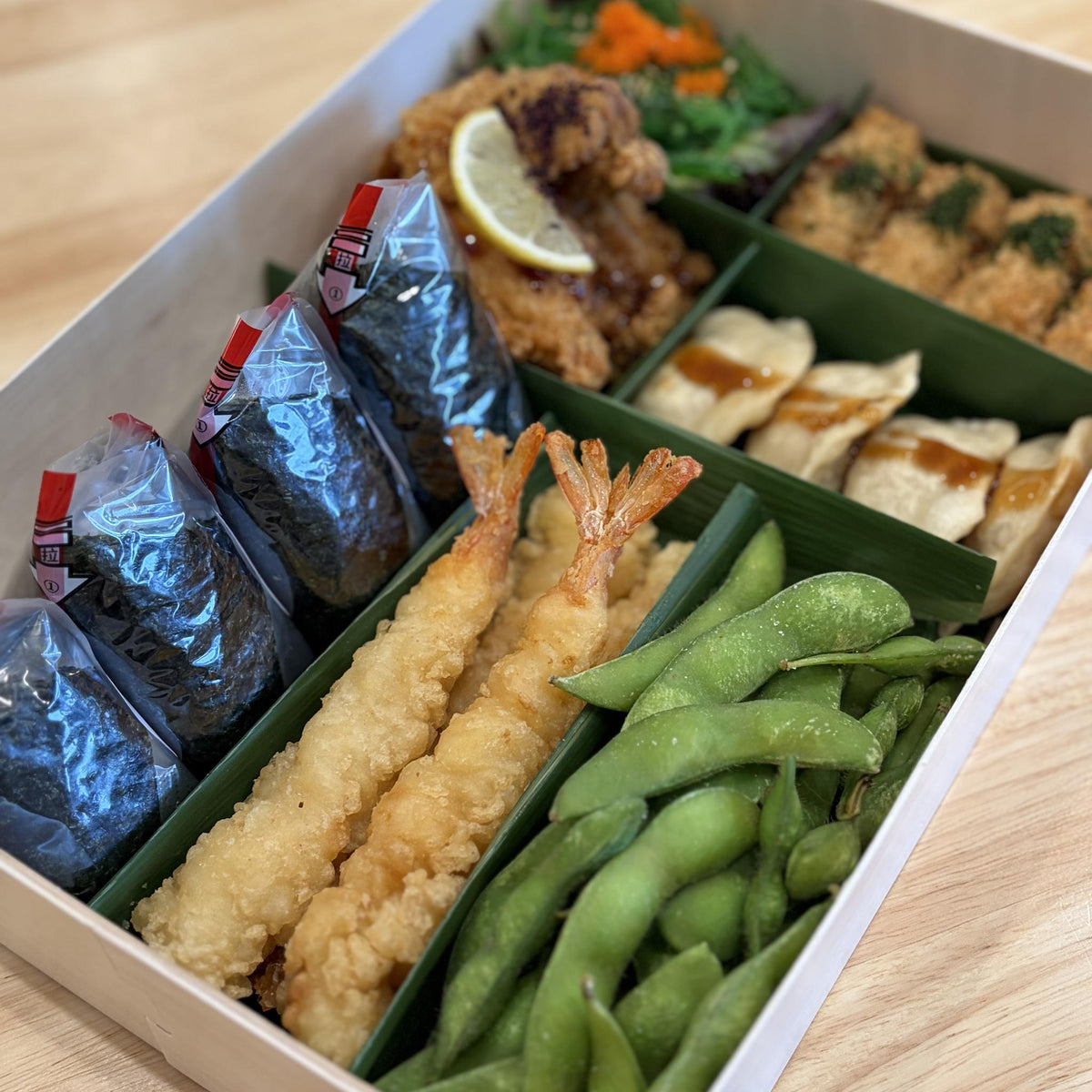 Savory Platter: onigiri, prawns, karaage, gyoza, kaki furai, seaweed salad and edamame in a wooden box